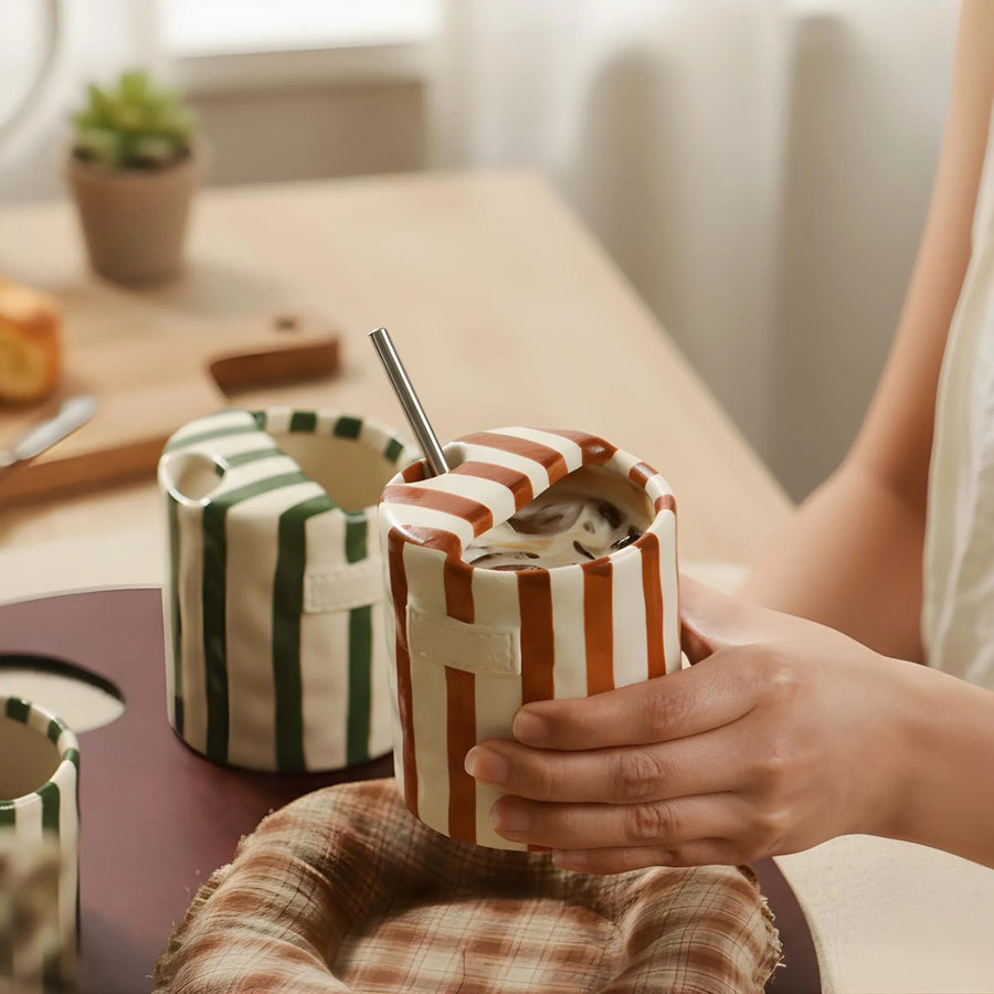 Hand-painted striped ceramic mug held in hand