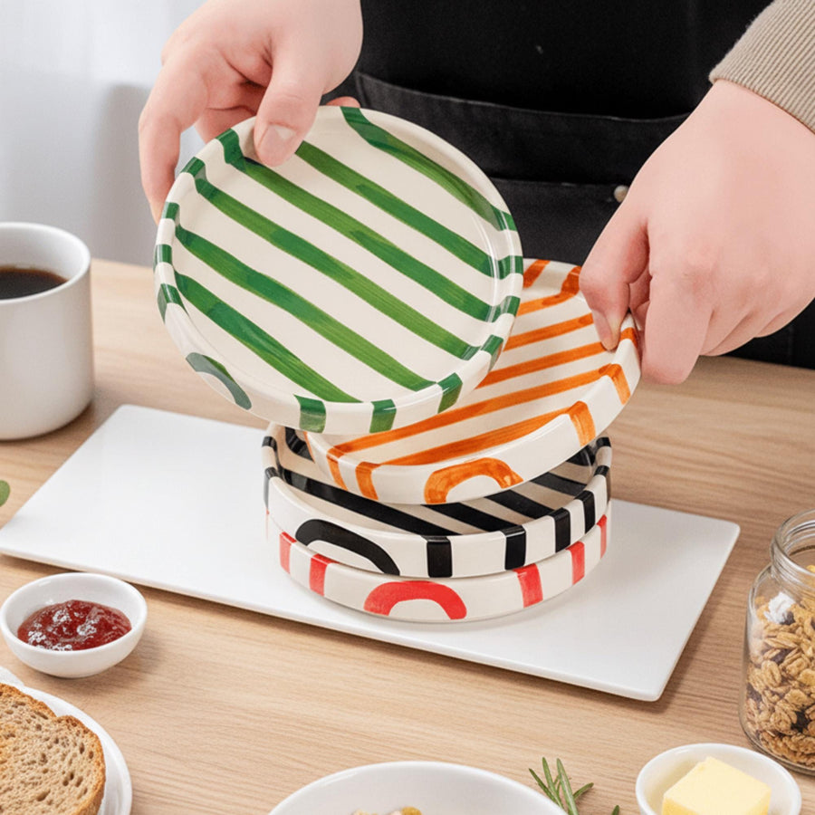 Striped ceramic side plate held above a table
