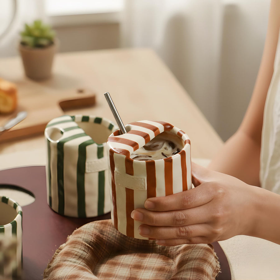 Hand-painted striped ceramic mug held in hand