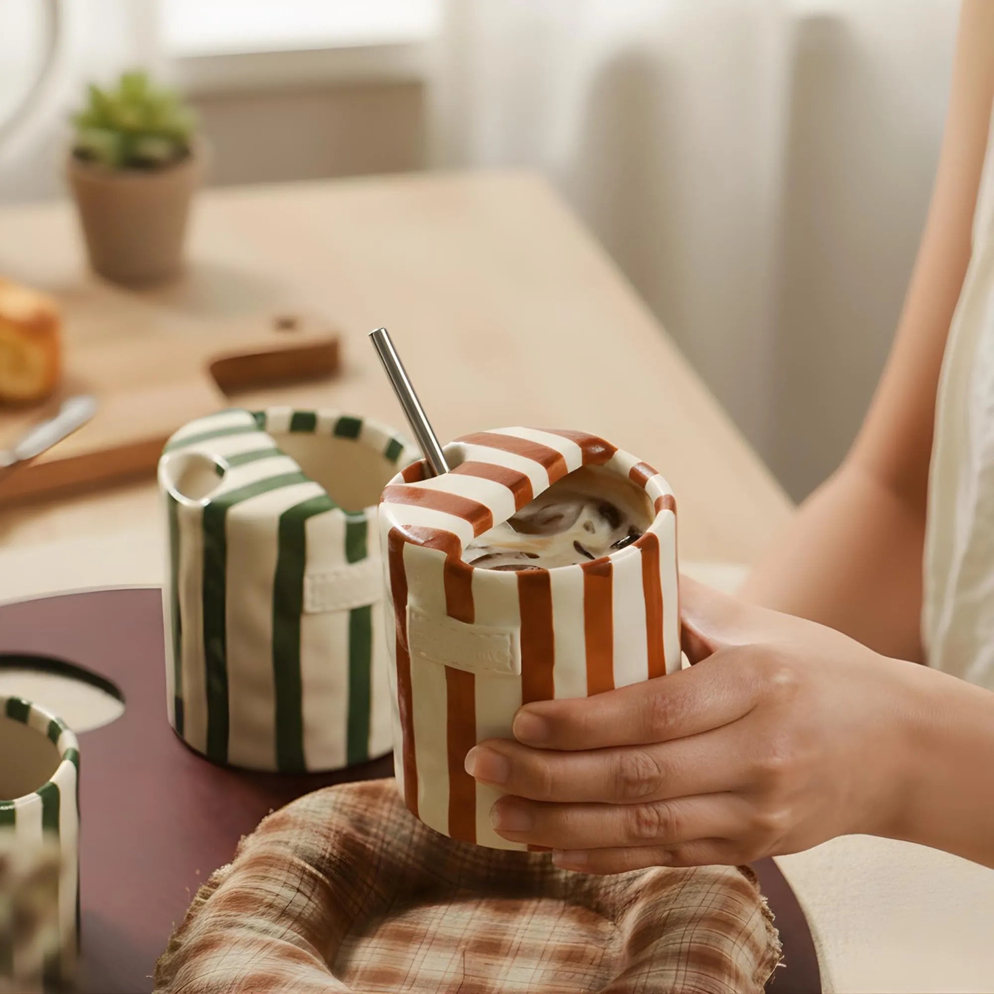 Hand-painted striped ceramic mug held in hand