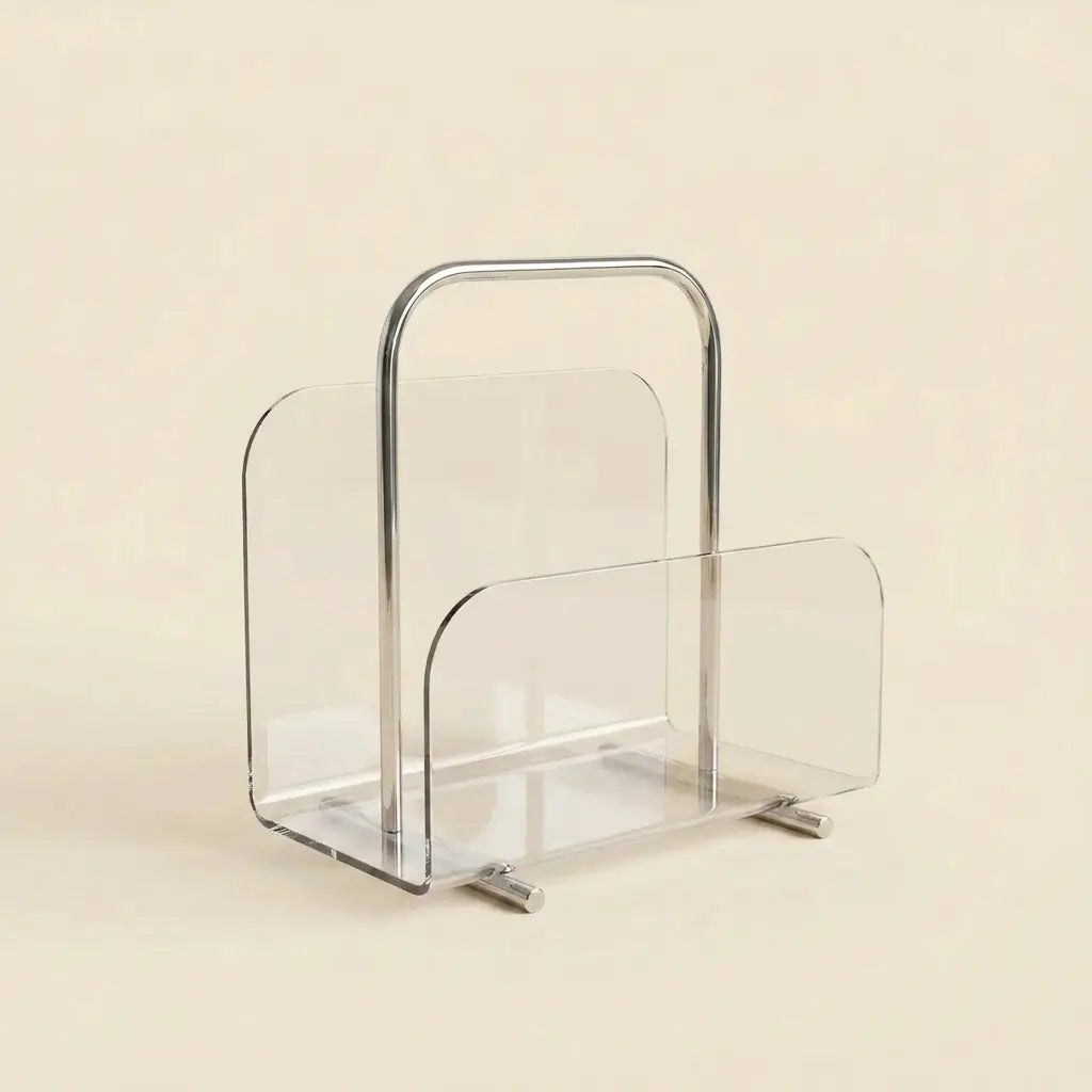 Clear Lucite Lumen Magazine Stand with a polished chrome carry handle, holding magazines